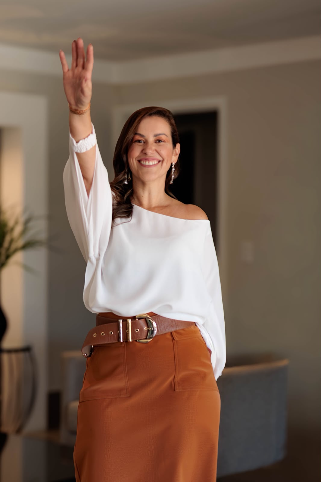 Renata sorrindo, com a mão levantada